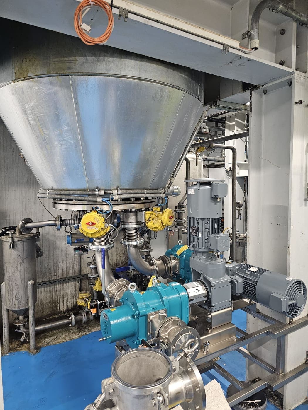 Trichter mit pneumatischen Armaturen, Pumpen und Getriebemotoren auf einem Rahmen.
